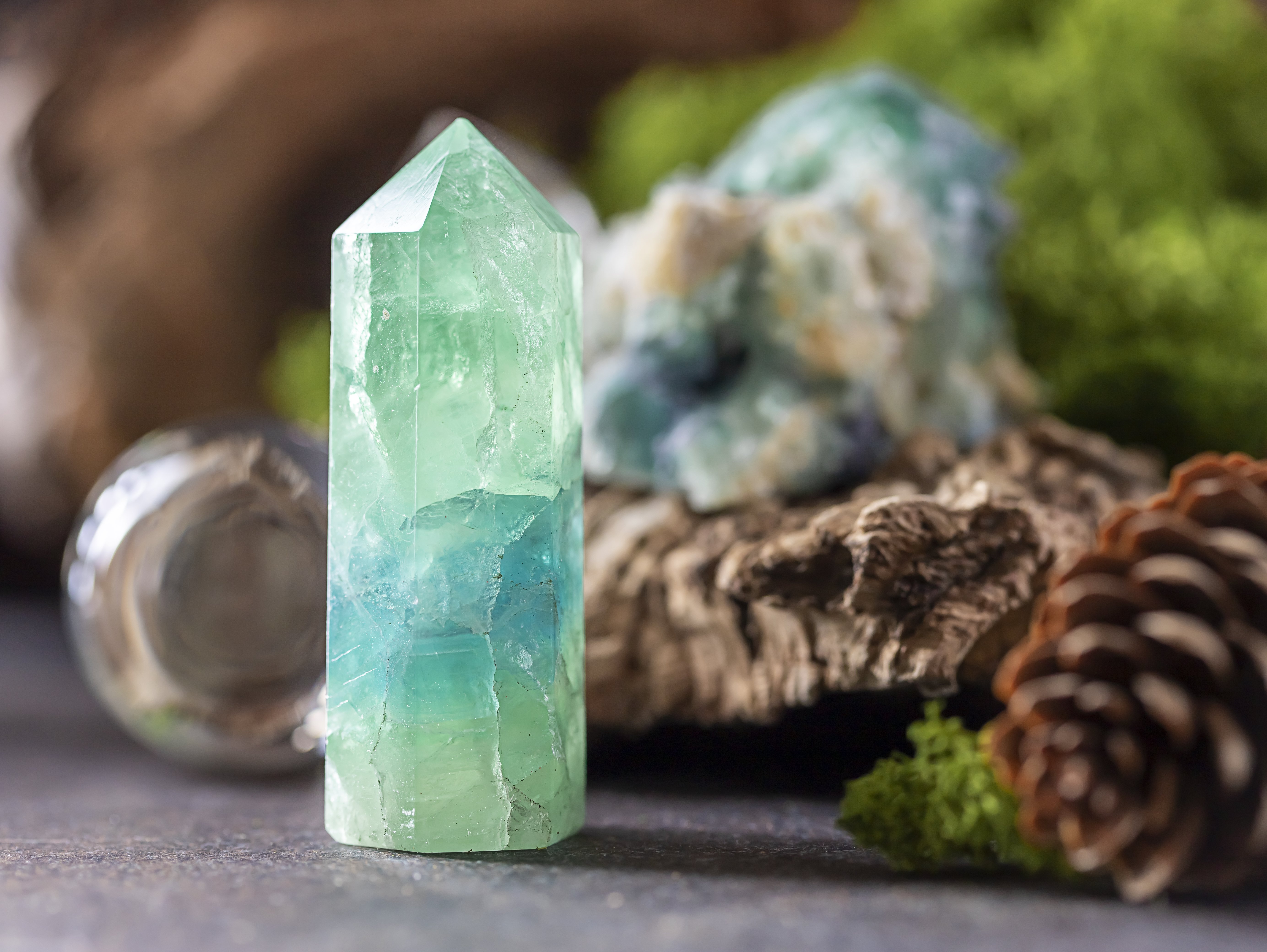 Blue crystal surrounded by pine cones and moss